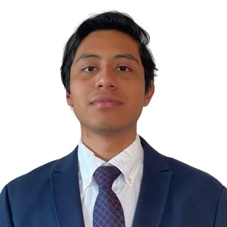 Fotografía de René Cano: retrato con saco azul marino, camisa blanca y corbata.